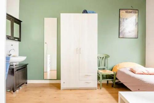 a bedroom with a white cabinet and a bed and a sink at Cozy private room in shared apartment, close to beach and city center in The Hague