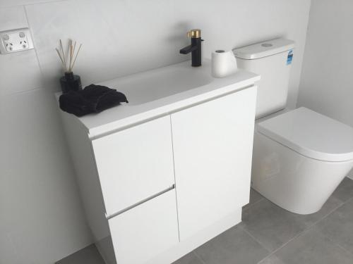 a bathroom with a white sink and a toilet at Captains Cottage - Pet Friendly Breakfast Included in Goolwa