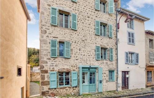 an old building with blue shutters on a street at 2 Bedroom Amazing Home In Olliergues in Olliergues