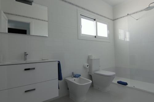 a white bathroom with a toilet and a sink at Costa Mar Sea View in Puerto del Carmen