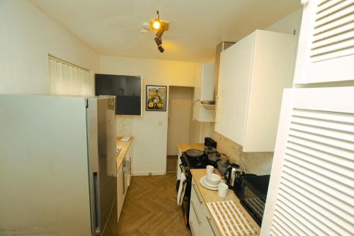 a kitchen with white cabinets and a refrigerator at Spacious 2 bed house, FREE parking, Gateshead in Gateshead