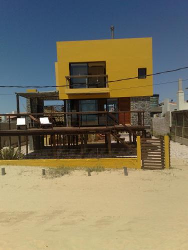 a yellow house sitting on top of a beach at Lobos de Mar in Punta Del Diablo