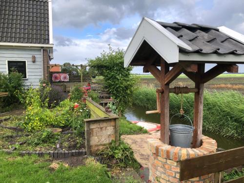 a garden with a wooden pergola and a pond at Appartement in schuur in Twisk
