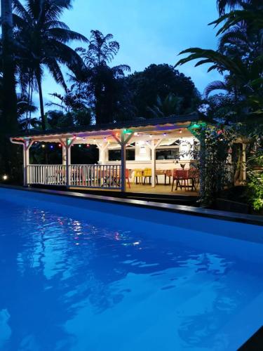 a swimming pool with a house in the background at Les Gîtes de la Lézarde in Petit-Bourg
