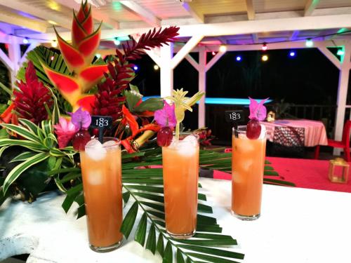 a table topped with four vases filled with drinks at Les Gîtes de la Lézarde in Petit-Bourg