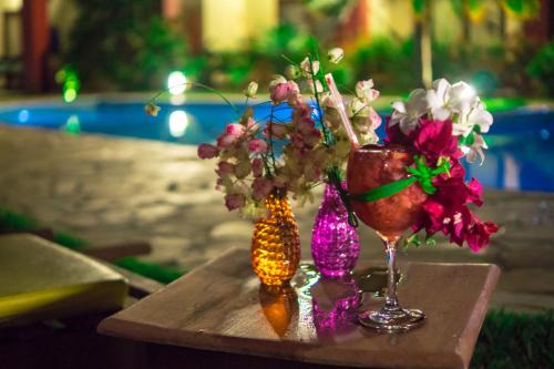 a table with a vase of flowers and a wine glass at Porto Zarpa Hotel in Praia do Forte