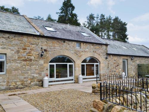 an old stone building with a large window at The Byres in Greenhaugh