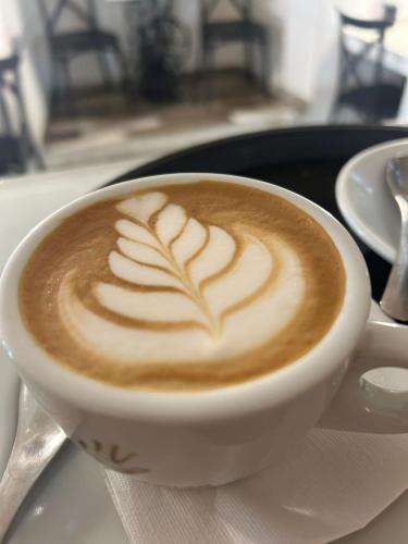a cup of coffee with a leaf pattern on a plate at Celine Confort Room in Modugno