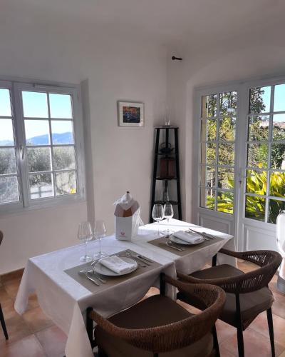 a dining room with a white table with chairs and windows at les petites terrasses in Grasse