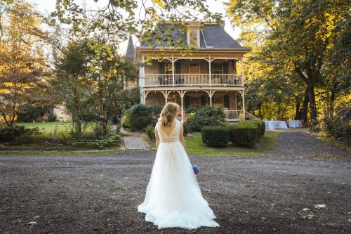 a woman in a wedding dress standing in front of a house at Fallen Tree Farm Bed and Breakfast in Carlisle
