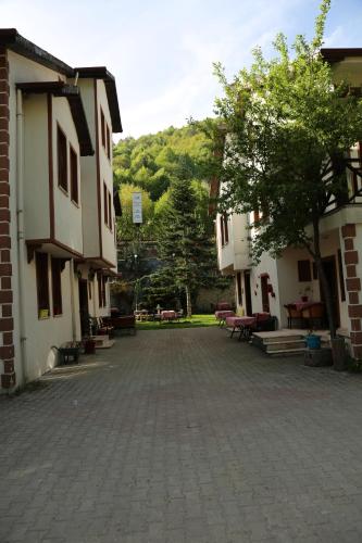 a courtyard of two buildings with benches and trees at ABANT DORT MEVSİM KONAĞI HOSTEL in Dereceören