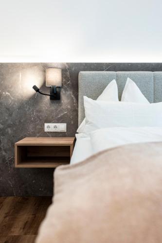 a bed with white pillows and a table with a lamp at Hotel Gasthof Brüggler in Radstadt
