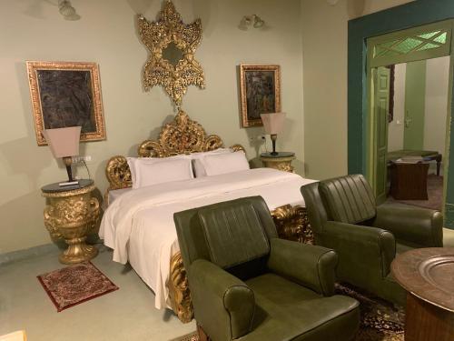 a bedroom with a large bed and two chairs at Partap Mahal in Bikaner