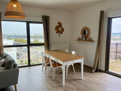 - une table et des chaises dans le salon doté d'une grande fenêtre dans l'établissement Appartement proche de la gare - 80m2, à Bordeaux