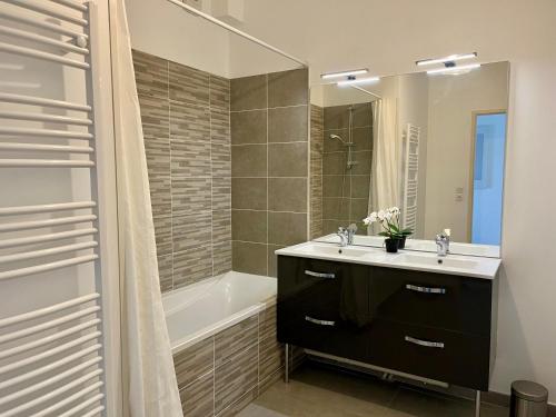 une salle de bain avec un lavabo, une baignoire et un miroir dans l'établissement Appartement proche de la gare - 80m2, à Bordeaux