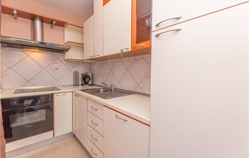 a kitchen with white cabinets and a sink at Two-Bedroom Holiday Home In Kijevo in Kijevo