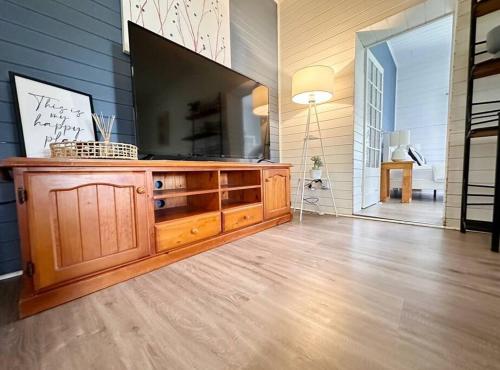 a living room with a large television on a wall at Byron Soul - Waterfront 3BR w Deck - Views in Wardell