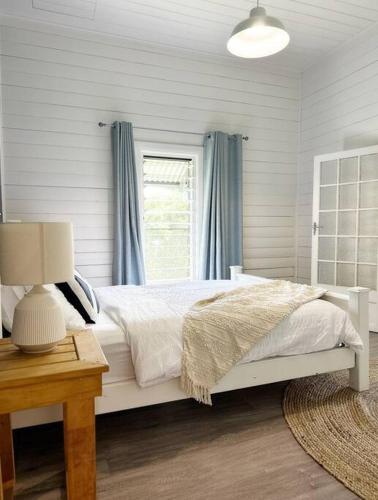 a bedroom with a white bed and a window at Byron Soul - Waterfront 3BR w Deck - Views in Wardell