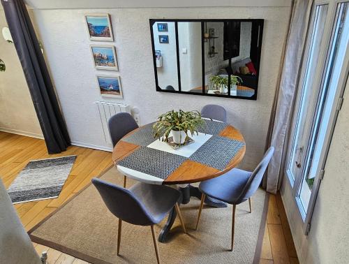 une table à manger avec des chaises bleues et un miroir dans l'établissement Maison de pêcheur - 200m de la plage, à Étretat