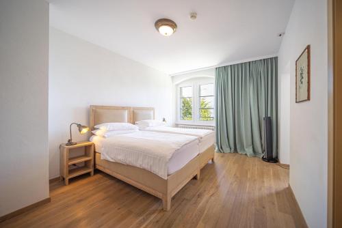 a white bedroom with a bed and a window at Au Major Davel in Cully