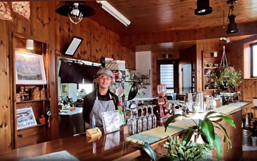 a man standing behind a bar in a kitchen at Guest House Honami-Kaido in Yamanouchi