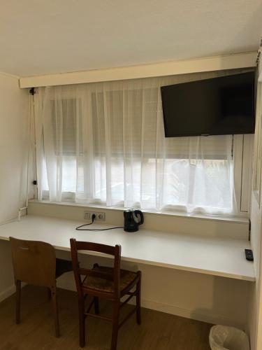 a desk with a television and a chair in a room at Kyriad Direct Metz Nord – Woippy in Woippy