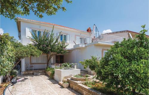 a white house with a balcony and trees at Three-Bedroom Apartment In Rogoznica in Rogoznica