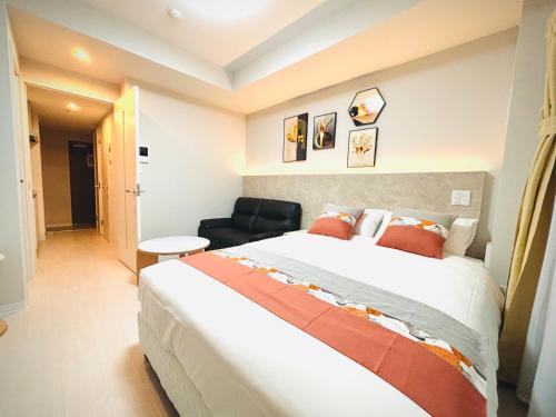 a bedroom with a large bed and a chair at Hotel Arashi Nambaminami No003 in Osaka