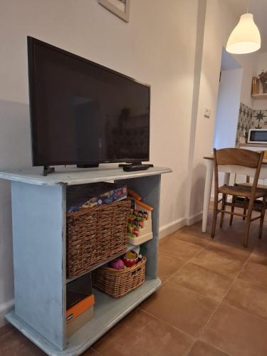 a flat screen tv on a tv stand with baskets at Casa Luisa - Casa Completa con Encanto Valdepeñas in Valdepeñas