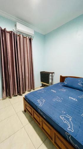 a bedroom with a bed and curtains and a chair at Bella Homestay in Kampong Bari Kechil