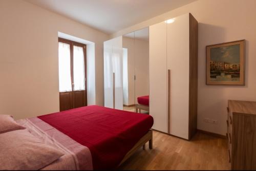 a bedroom with a bed with a red blanket at Sotto La Torre in LʼAquila