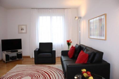a living room with a black couch and a chair at 1BR apartment close to Opera - SF7 in Zürich