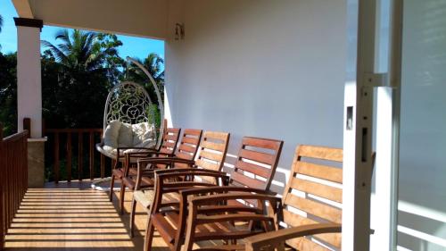 a row of wooden chairs sitting on a porch at Cogent Holiday Home in Gelioya