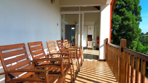 a row of wooden chairs sitting on a porch at Cogent Holiday Home in Gelioya