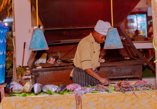 een man die eten klaarmaakt op een tafel op een markt bij Baraka Beach Bungalows in Nungwi