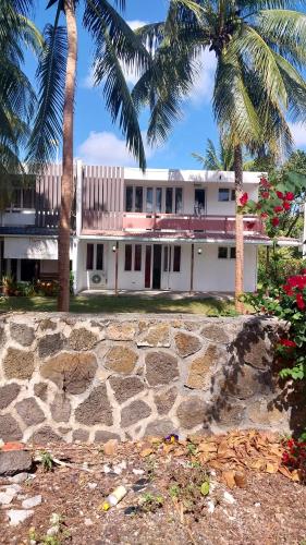 a white building with palm trees in front of it at Pereybère Apartment in Pereybere
