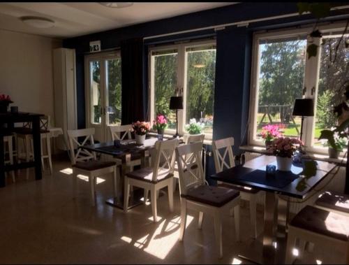 a dining room with a table and chairs and windows at Hammarö Vandrarhem in Hammarö