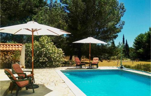 - une piscine avec 2 chaises et 2 parasols à côté dans l'établissement Cozy Home In Pouzols-Minervois, à Pouzols-Minervois