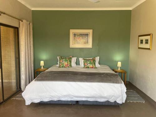 une chambre avec un grand lit aux murs verts dans l'établissement Lekker Plekkie Farm Cottage, à Hekpoort