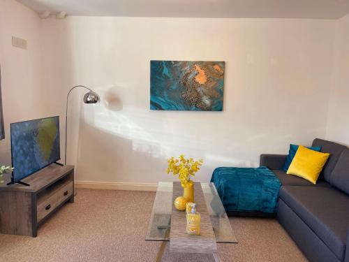 a living room with a couch and a tv at Elegant Serviced Apartment with Parking in Oxford in Oxford