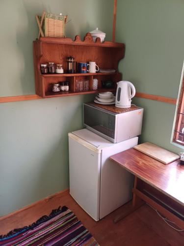 a small refrigerator and a table in a kitchen at The Farmhouse Palm Tree Cabin in Stellenbosch