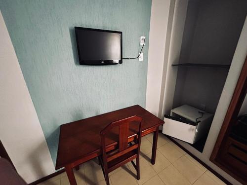 Habitación pequeña con mesa y TV en la pared. en MAGA PLAZA HOTEL, en São José do Rio Pardo