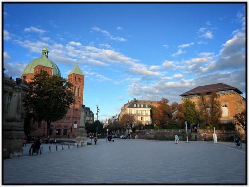 a building with a clock tower in the middle of a plaza at Ô Jardin Secret in Oberschaeffolsheim
