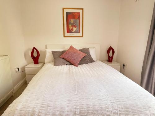 a bedroom with a white bed with red pillows at Lovely Serviced Apartment, Free Parking, Oxford in Oxford