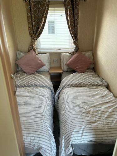 two twin beds in a small room with a window at J&D by the sea in Heysham