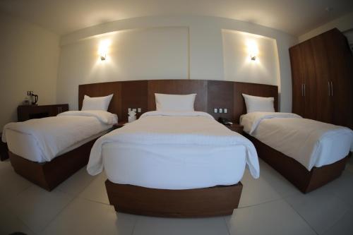 two beds in a hotel room with white sheets at Coral Karbala Hotel in Karbalāʼ