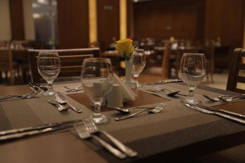 a table with glasses and utensils on a table at Coral Karbala Hotel in Karbalāʼ