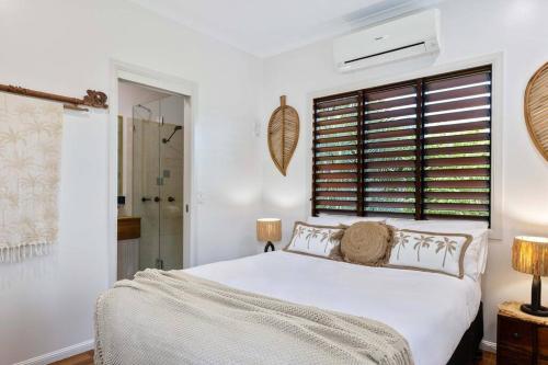 a white bedroom with a bed and a window at Melaleuca Villa with Private Pool in Port Douglas