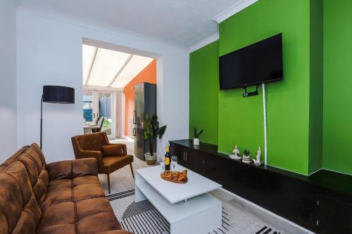 a living room with a couch and a green wall at The Lyme Lounge - Elegant & Contemporary 3BR Home - Sleeps 7 with Parking & WiFi - Ideal for Business Stays by Parydise Properties in Longport