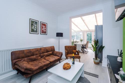 a living room with a brown leather couch and a table at The Lyme Lounge - Elegant & Contemporary 3BR Home - Sleeps 7 with Parking & WiFi - Ideal for Business Stays by Parydise Properties in Longport